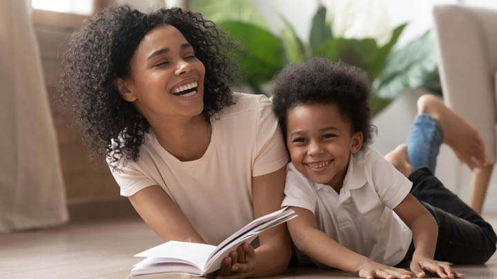 laughing mother reading book with young boy