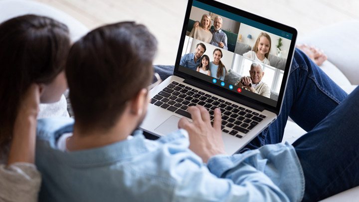 Man and woman sitting on sofa on a video call on laptop