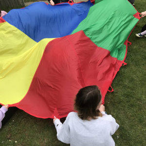 Anonymous picture of adults and children holding colourful parachute