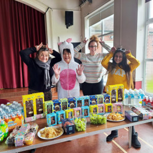 Staff making bunny ears in front of table of Easter eggs