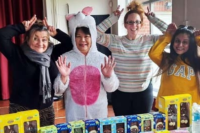 Four staff making bunny ears in front of a table of Easter eggs