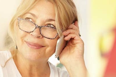 Woman wearing glasses smiling while talking on phone