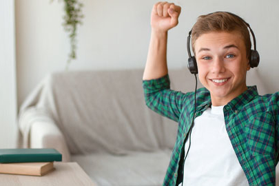Teenage boy celebrating with headphones on at desk