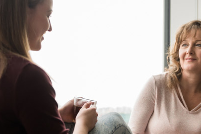 A teenager sitting with a cup of tea with female foster carer