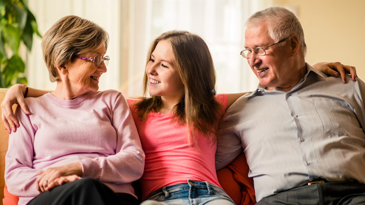 Teenage girl on sofa between foster carers