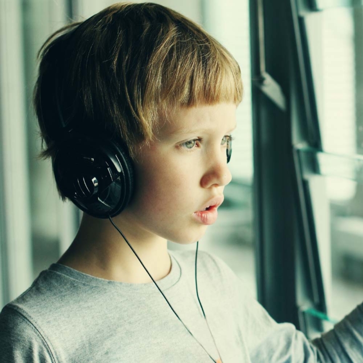 Autistic boy wearing headphones looking out of window