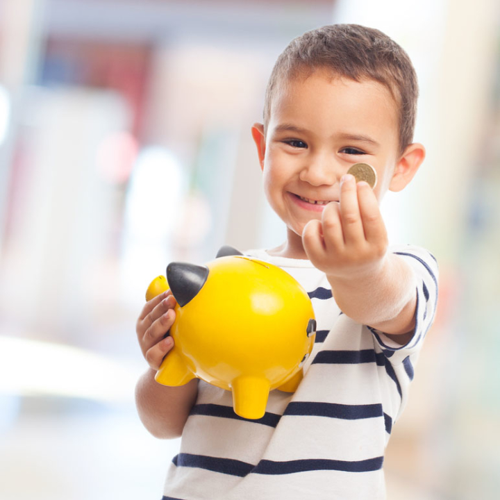 portrait of a little boy putting money on a moneybox